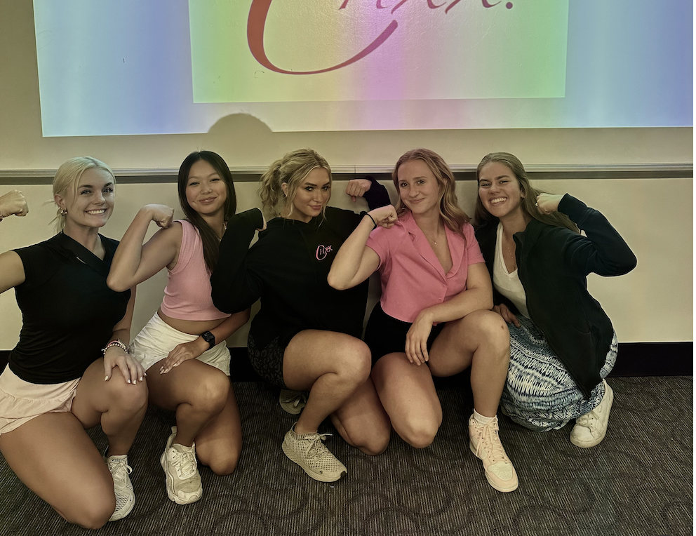 Group of women in hoodies flexing and laughing together